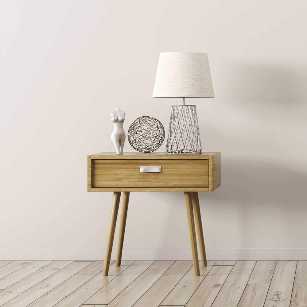 Beistelltisch mit Schublade aus Holz mit einer Lampe und weiteren Dekoelementen